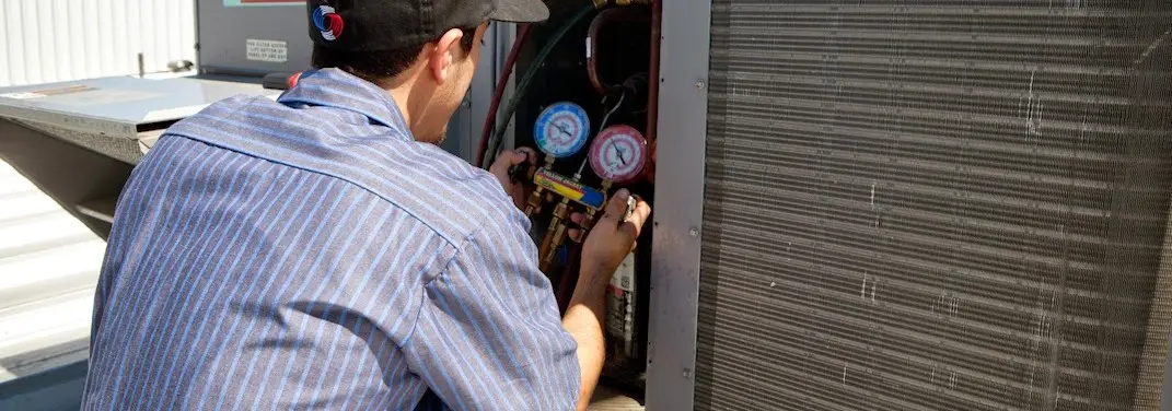HVAC technician servicing a condenser unit in Douglass Hills